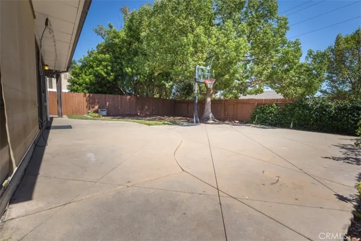 Spacious backyard with hardscape, basketball hoop and gorgeous shade tree.