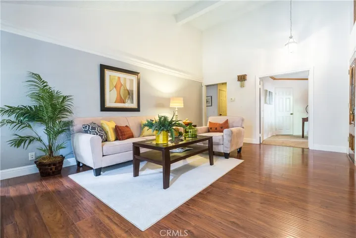 Alternate view of the staged family room with wide baseboards, high ceilings and attractive wood laminate flooring.