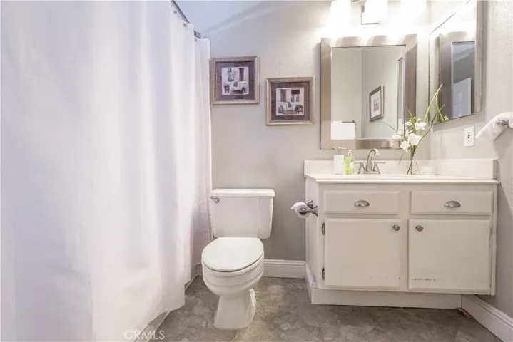 Second bathroom with vinyl tile floors, and convenient shower in bathtub.