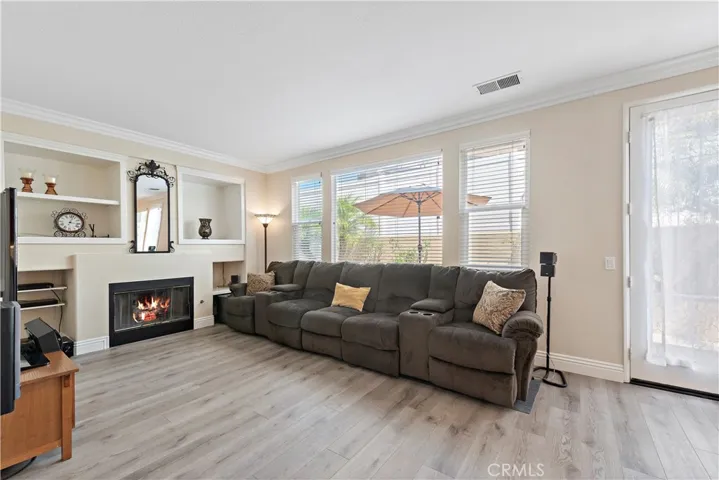 The large family room features a cozy gas fireplace and media niches for your entertainment needs. Notice the crown molding and the luxury vinyl floors.