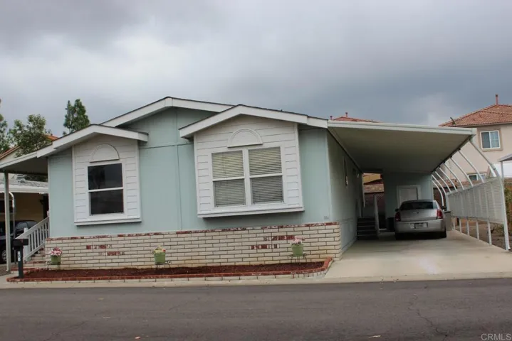 View of home showing attractive colors, masonary skirting and extra wide carport area.