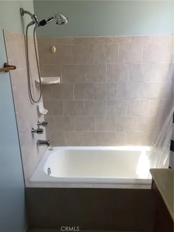 Bath/shower with tile enclosure and hand-held shower.