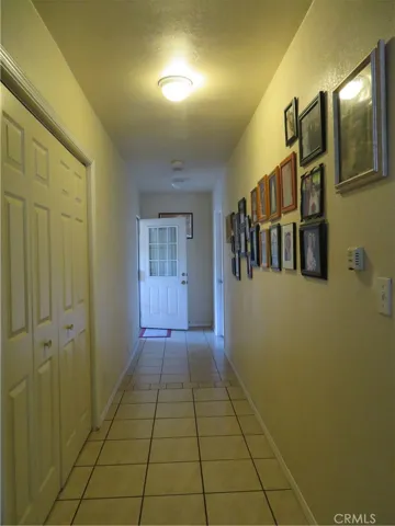 Wide hallway view toward the backyard door entry. inside laundry door panels on the left side.