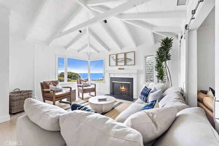 Living room with gorgeous beamed ceilings, coastline views. and cozy fireplace.