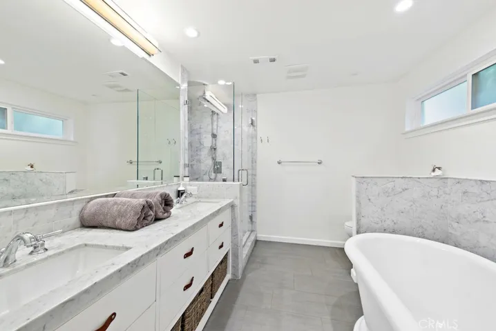 Luxurious master bath adorned in marble with dual sinks and separate soaking tub and walk-in shower.