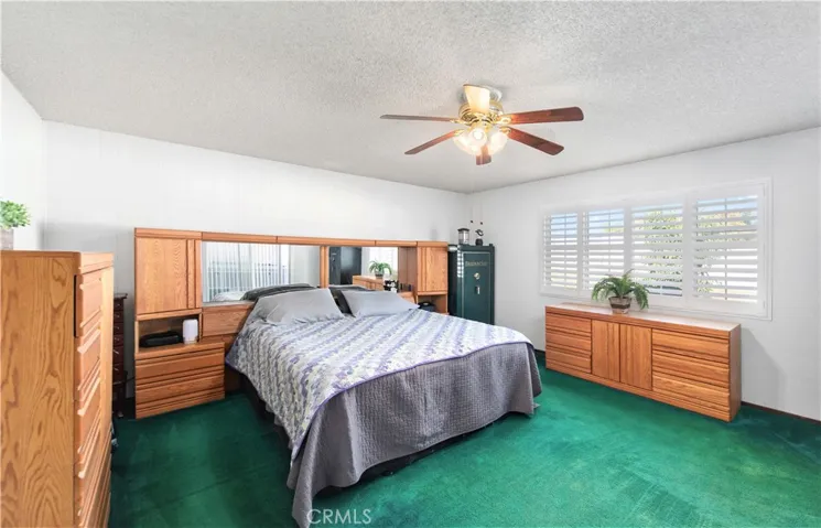 Large primary bedroom with Plantation shutters and ceiling fan