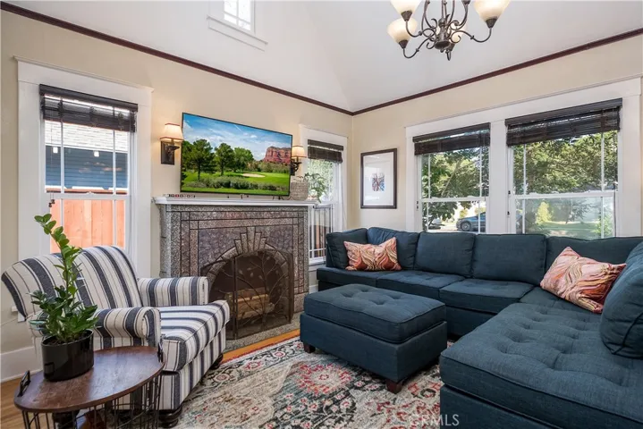 The darling living room is focused around a faux fireplace and accented by soaring ceilings and gorgeous hardwood floors