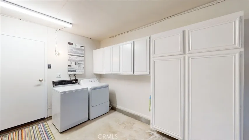 Laundry in the direct access garage with ample wall mounted  storage cabinets.