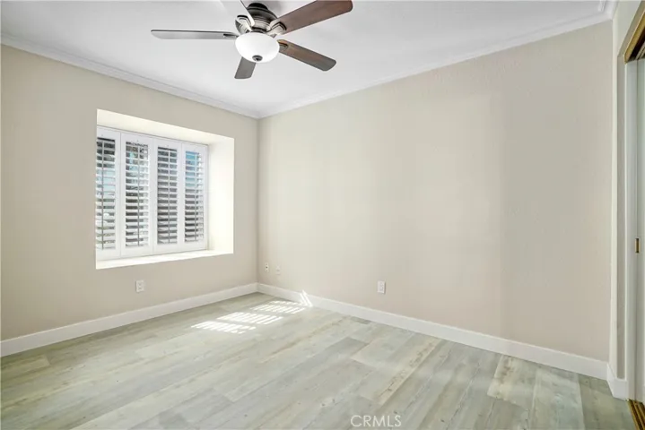 Downstairs bedroom with ceiling fan and laminate flooring