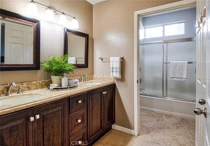 Spacious bathroom with dual sinks, warm woods, and silver accents.