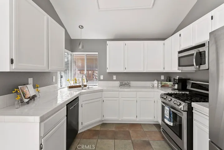 Vaulted Ceilings in you lovely kitchen with a corner sink & windows looking out to rear yard, tile flooring, Bosch dishwasher, stove & built in microwave.