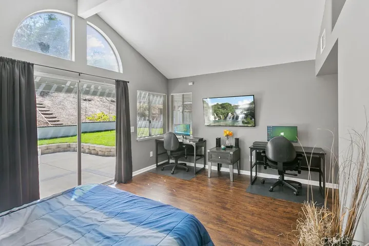 Another view of the Primary Bedroom with vaulted ceilings, laminate flooring, glass slider leading to rear yard & walk-in closet.