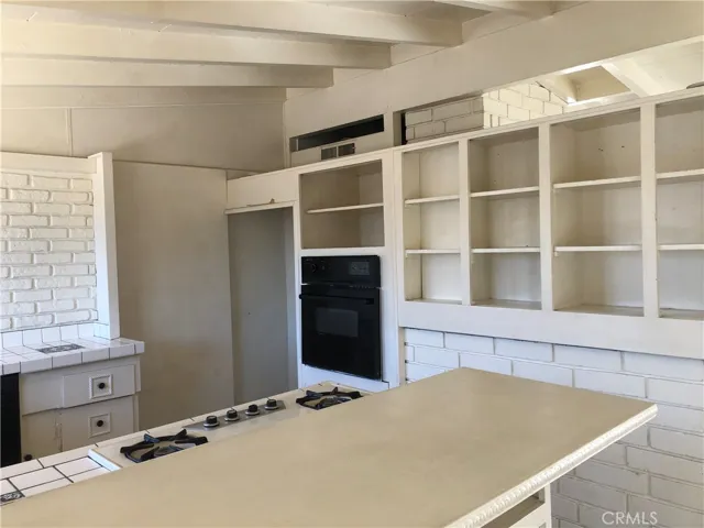 A wall oven and lots of shelves next to the oven.