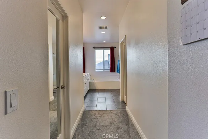 Master suite bathroom with two walk-in closets on either side of hall