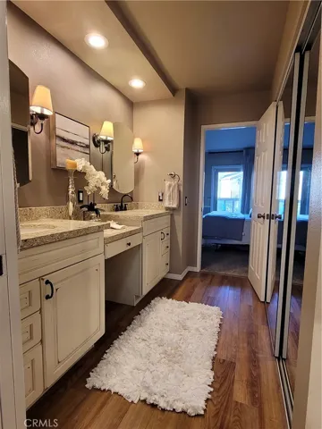Double sinks and vanity area on the left. Mirrored closets on the right.