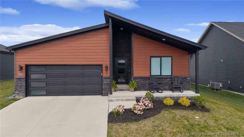 Modern 2024-built home with attractive landscaping, covered entry, and attached 2-car garage