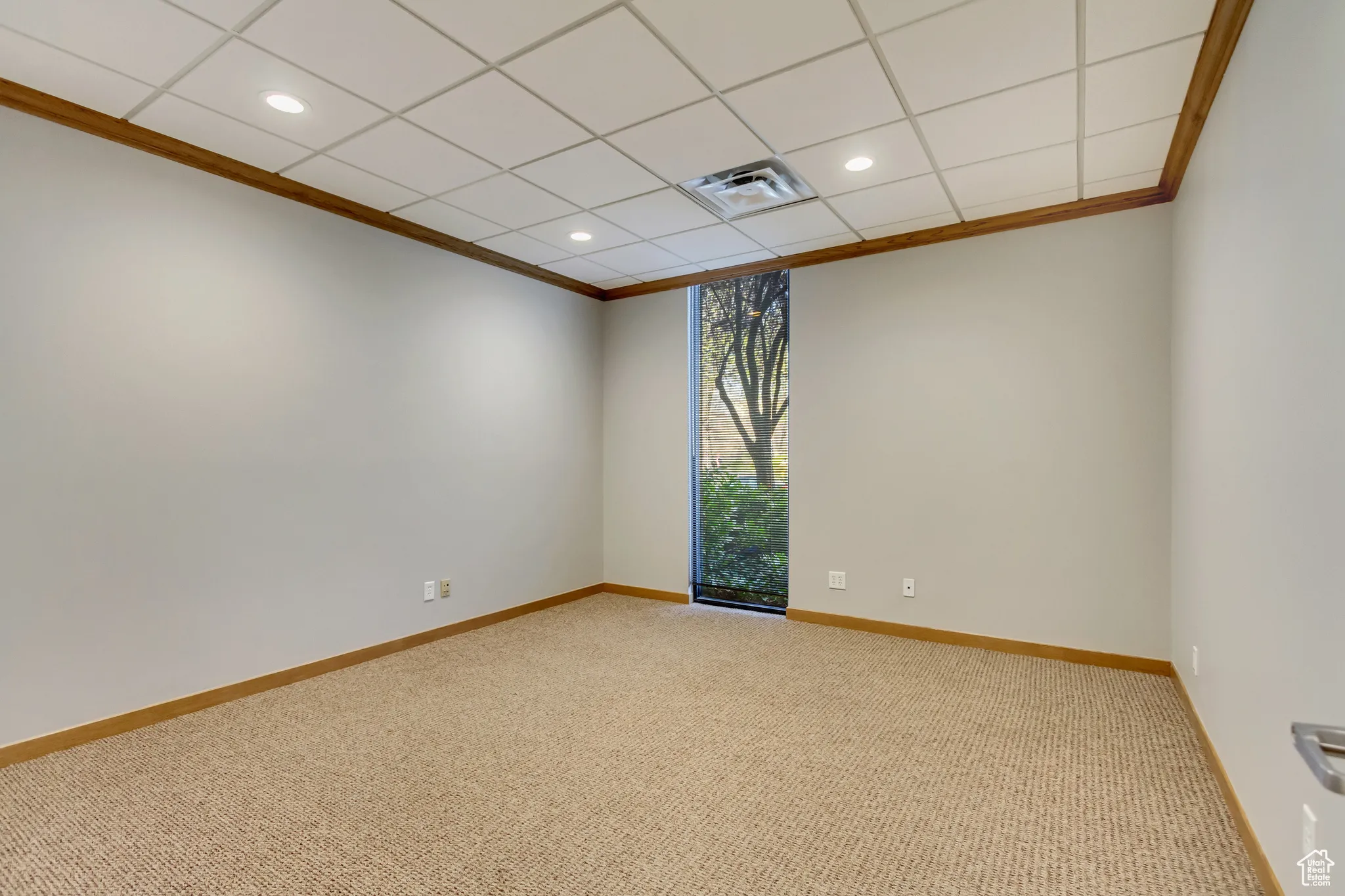 Empty room featuring carpet flooring, visible vents, baseboards, recessed lighting, and ornamental molding