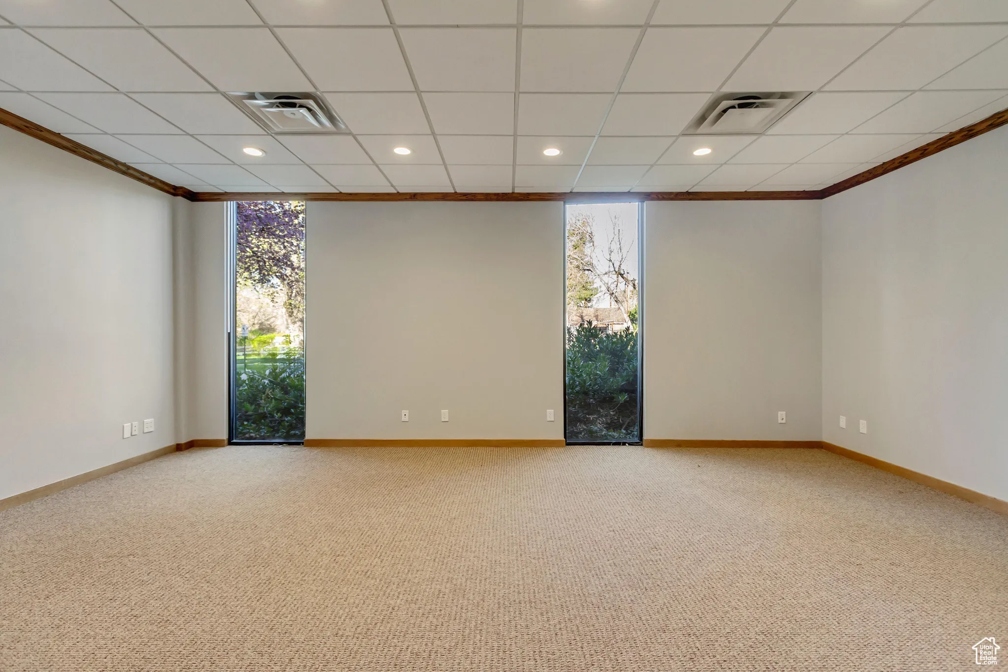 Carpeted empty room featuring visible vents, a wealth of natural light, and ornamental molding
