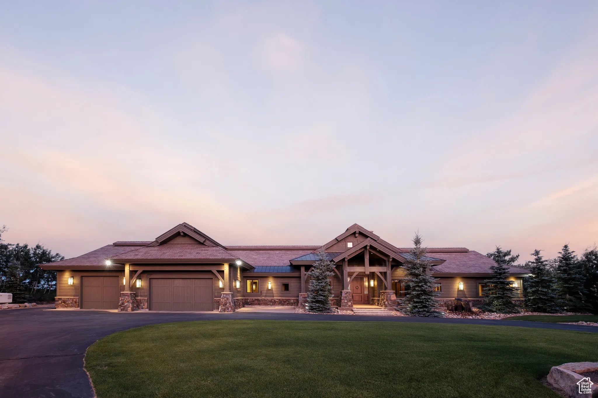 View of front of property featuring a lawn, driveway, stone siding, and a garage