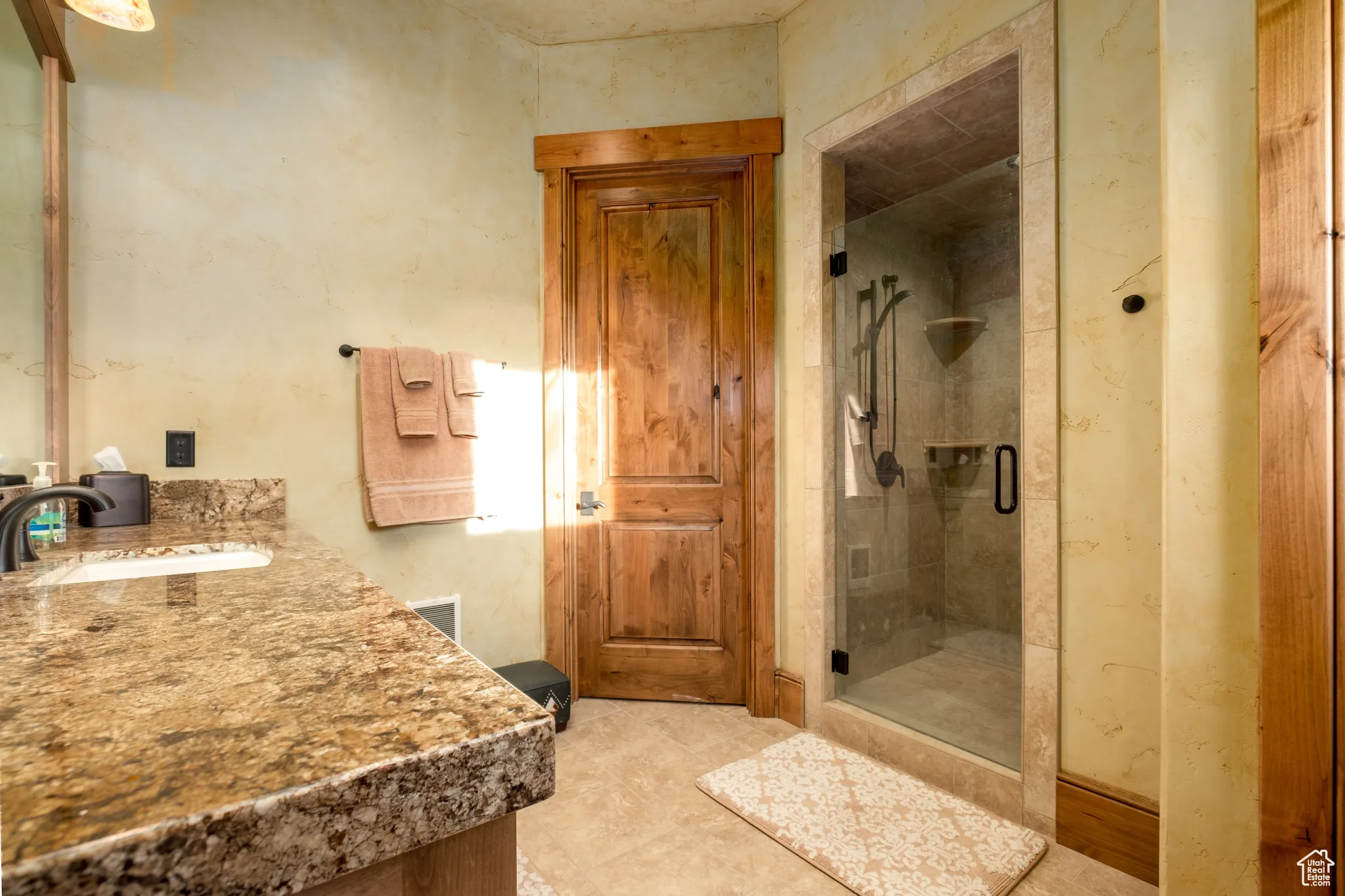 Full bathroom with vanity, a shower stall, and visible vents
