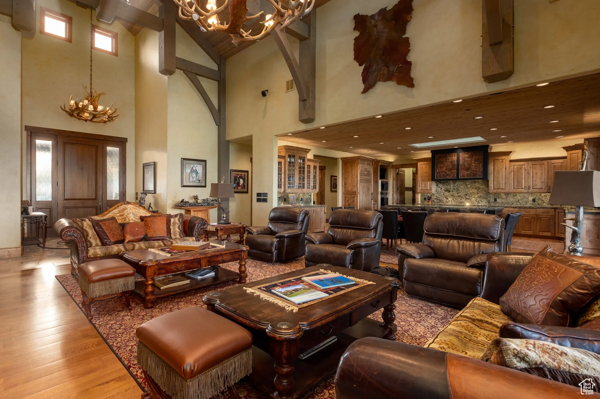 Living area with light wood-style floors, recessed lighting, a towering ceiling, and a notable chandelier