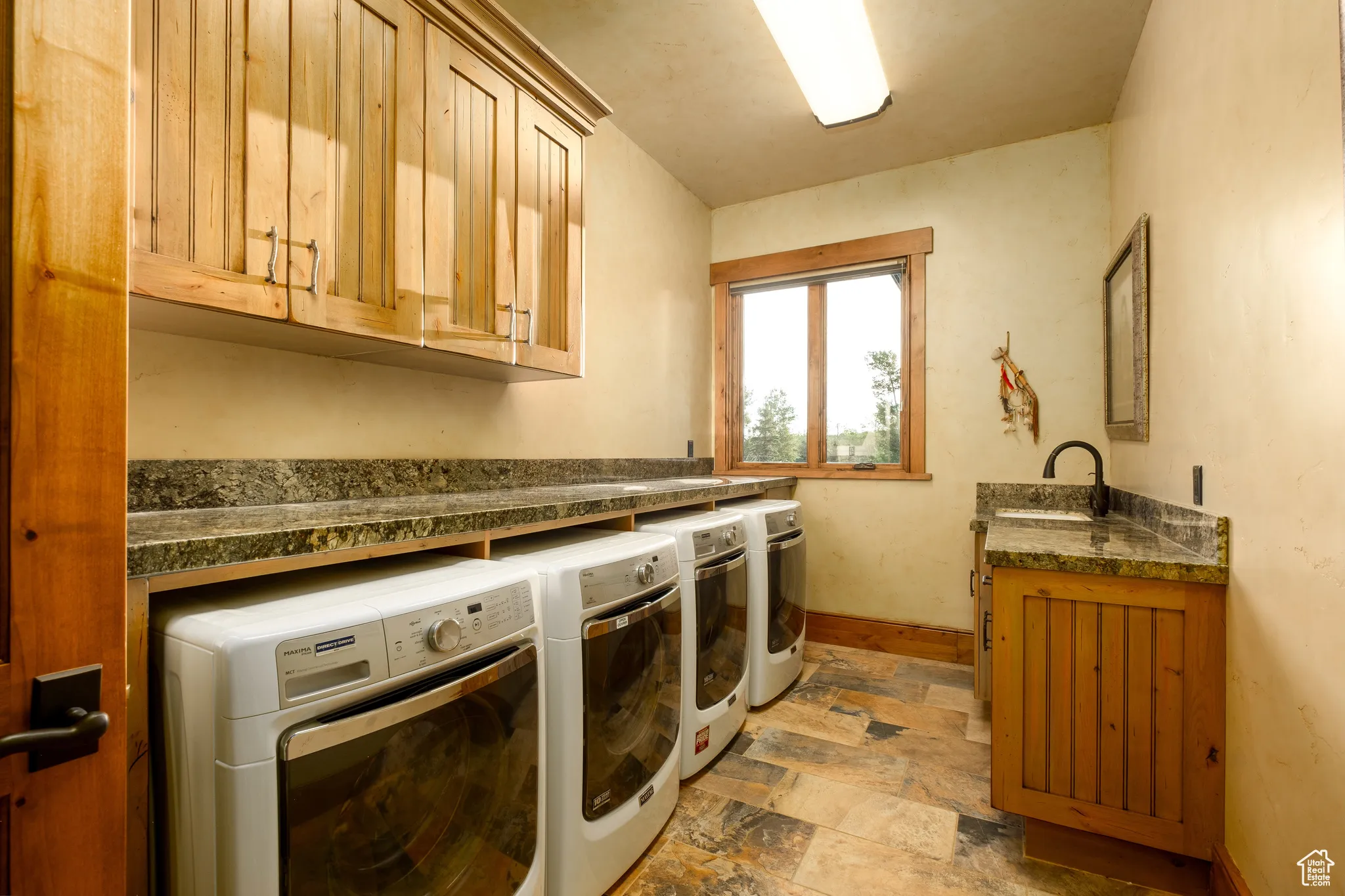 Washroom featuring cabinet space, a sink, stone finish floor, baseboards, and washer and clothes dryer
