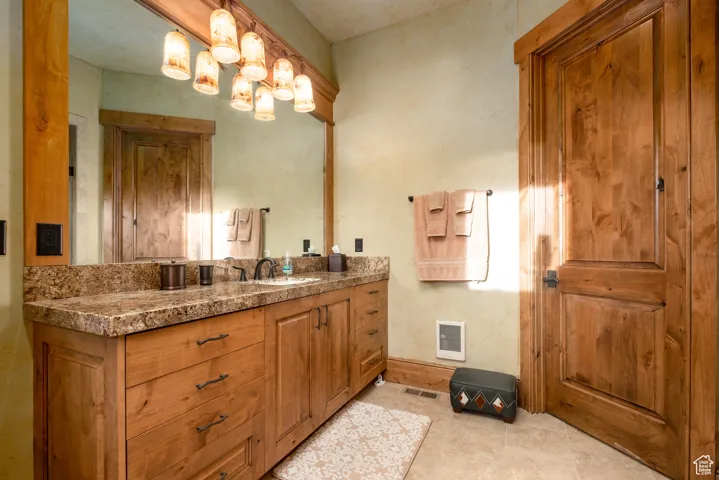 Bathroom with an inviting chandelier, vanity, tile patterned flooring, and visible vents