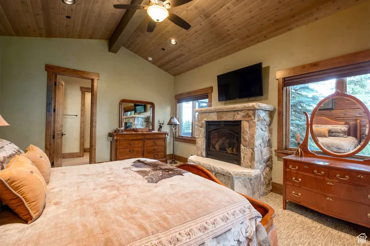 Bedroom featuring a fireplace, vaulted ceiling with beams, recessed lighting, light colored carpet, and a ceiling fan