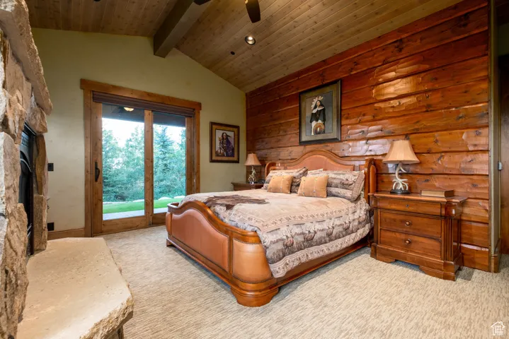 Carpeted bedroom featuring access to outside, wooden ceiling, vaulted ceiling with beams, and a fireplace