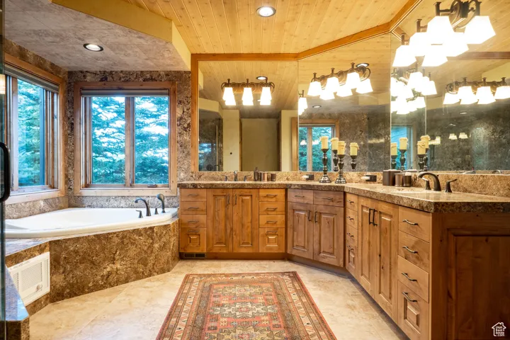 Full bath featuring a sink, wooden ceiling, wooden walls, and a bath