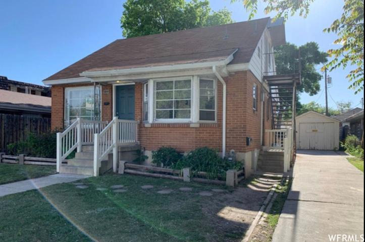 Bungalow-style home featuring a front lawn, garage, and a shed