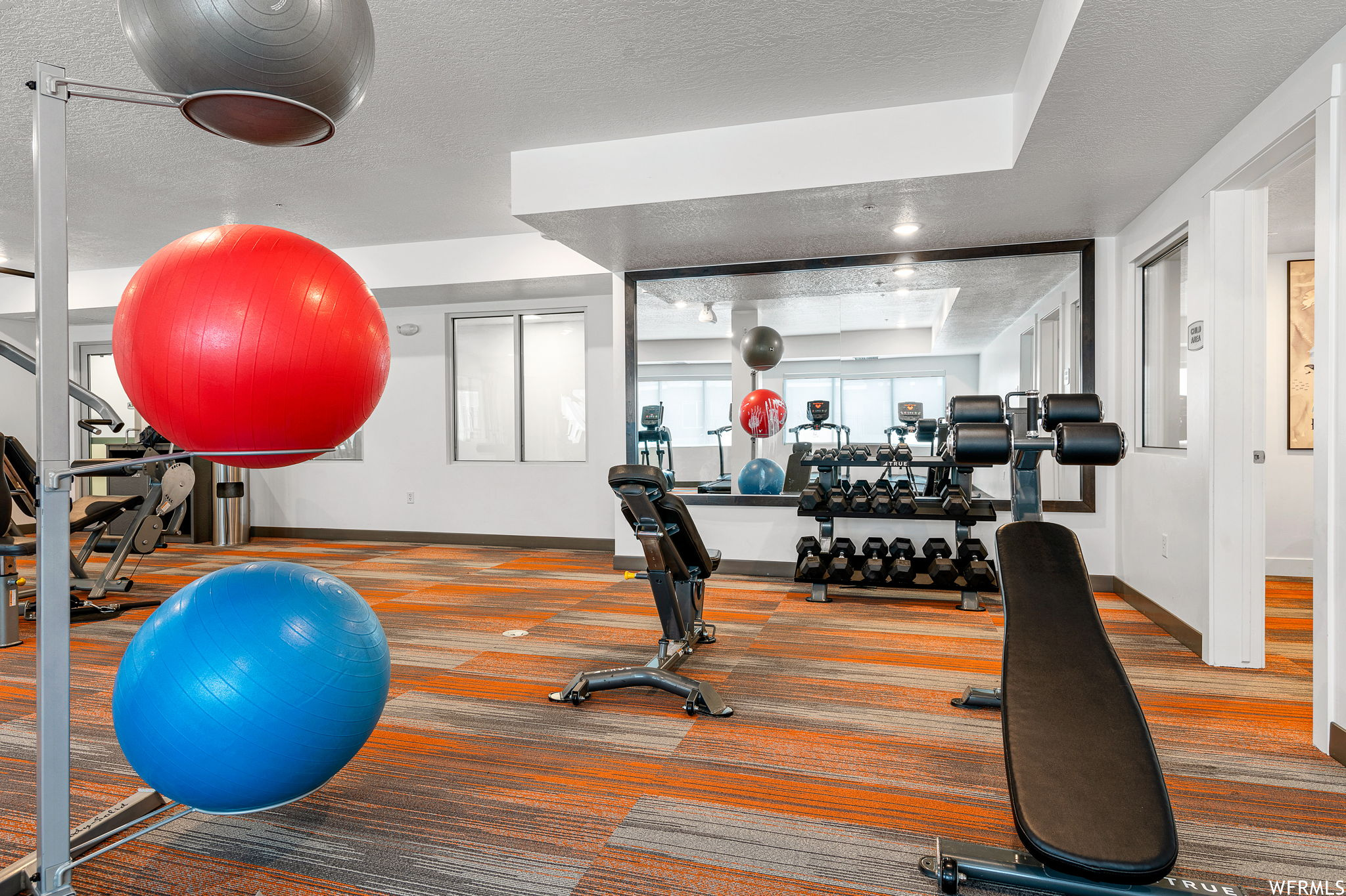 Workout room with a tray ceiling and a textured ceiling