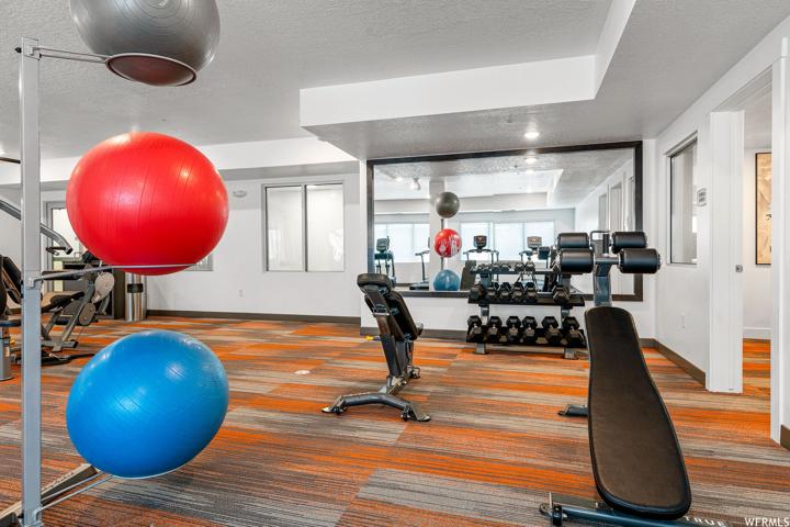Workout room with a tray ceiling and a textured ceiling