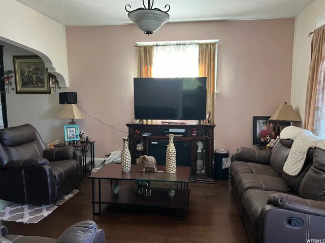 Living room with a textured ceiling and dark wood-type flooring