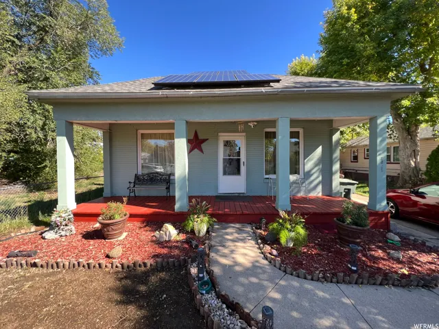 View of front of property featuring solar panels and covered porch