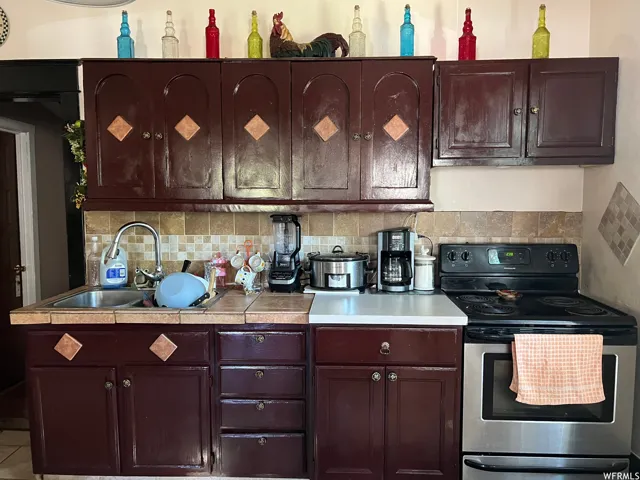 Kitchen featuring stainless steel electric stove, tasteful backsplash, and sink