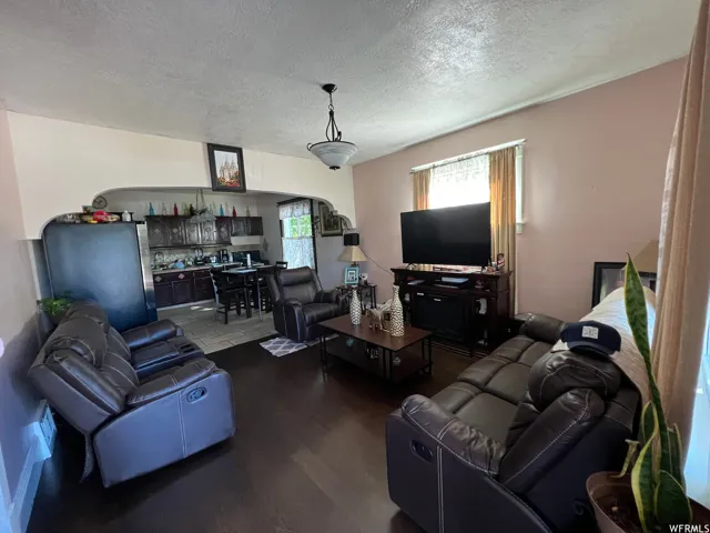 Living room featuring a textured ceiling and dark wood-type flooring
