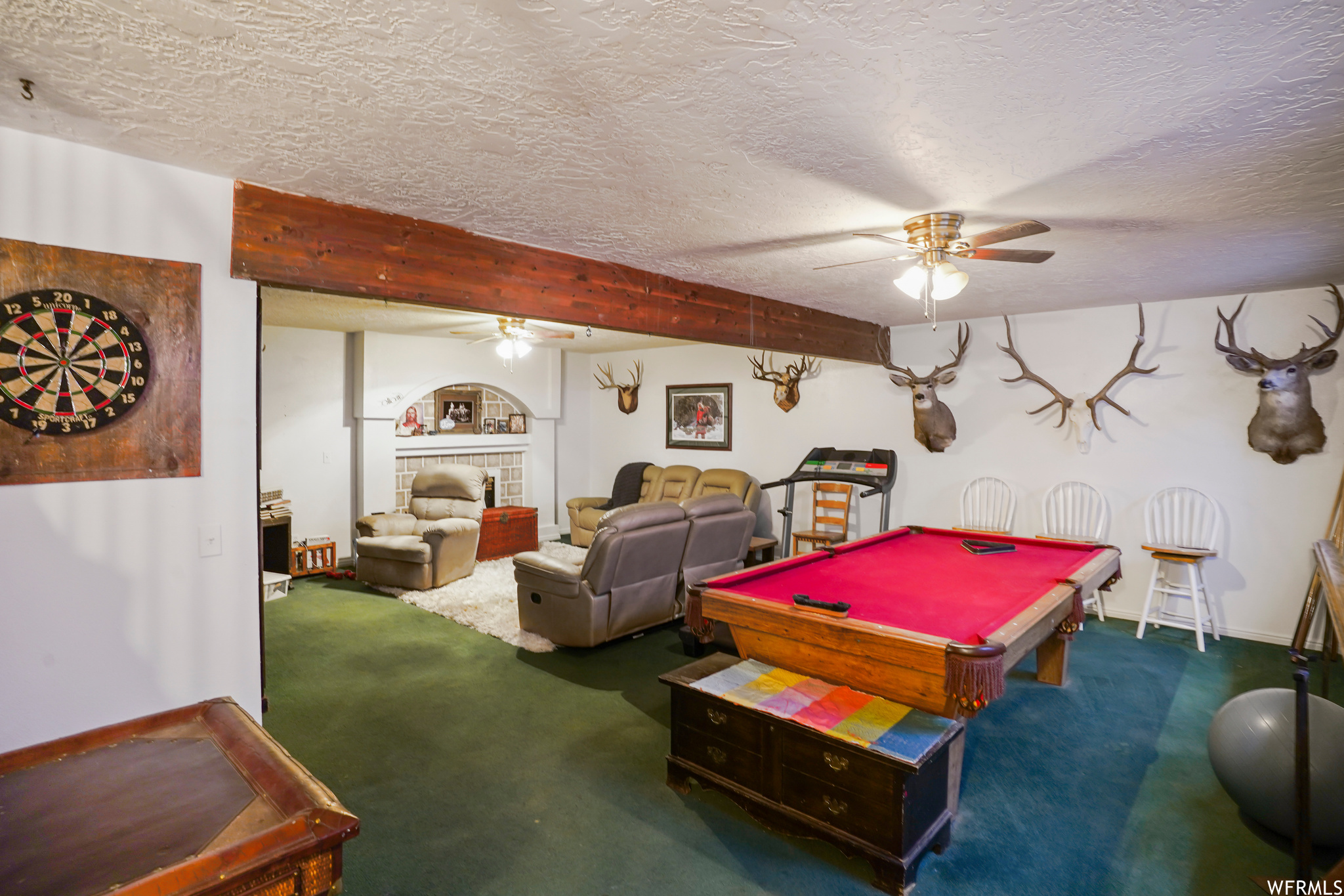 Recreation room featuring beamed ceiling, dark colored carpet, ceiling fan, a textured ceiling, and billiards