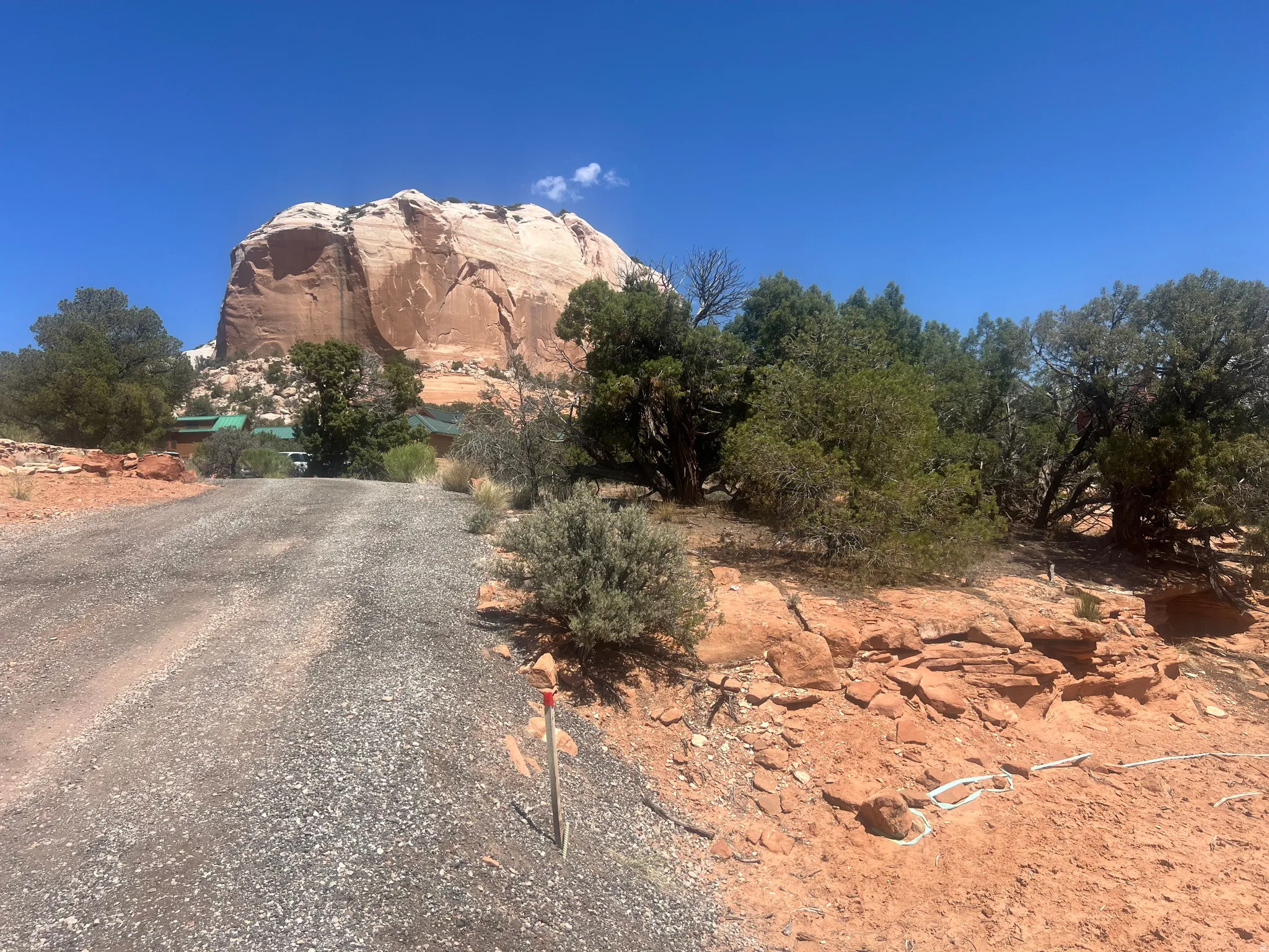Gravel driveway ascending towards the property, framed by natural rock formations and abundant desert flora