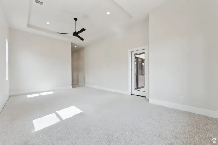 Spare room with ceiling fan, visible vents, light colored carpet, baseboards, and recessed lighting