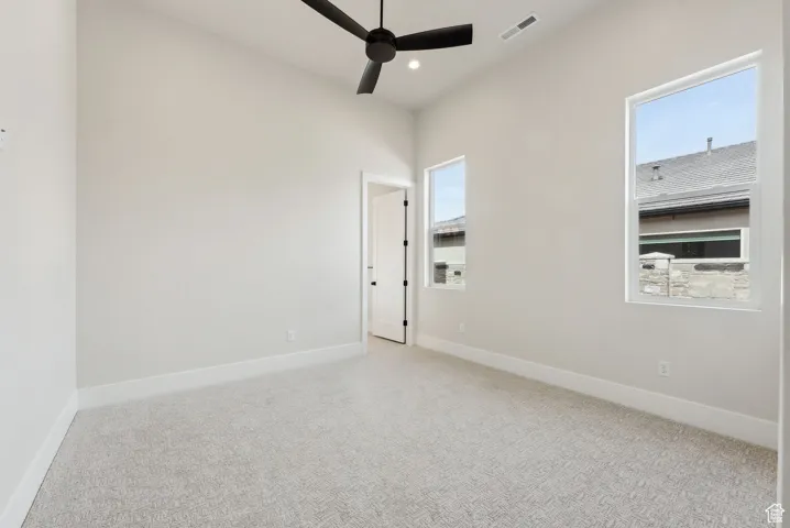 Carpeted spare room with baseboards, ceiling fan, and visible vents