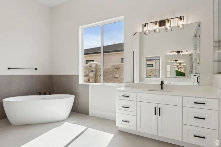 Bathroom with vanity, a shower with door, a freestanding tub, and a wainscoted wall