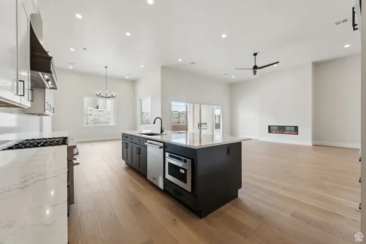Kitchen with recessed lighting, a sink, appliances with stainless steel finishes, and ceiling fan with notable chandelier