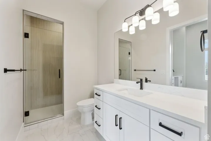 Full bathroom with a stall shower, vanity, baseboards, toilet, and marble finish floor