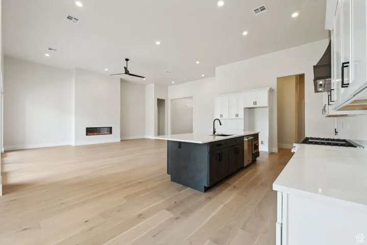 Kitchen with a sink, a ceiling fan, white cabinetry, and light countertops