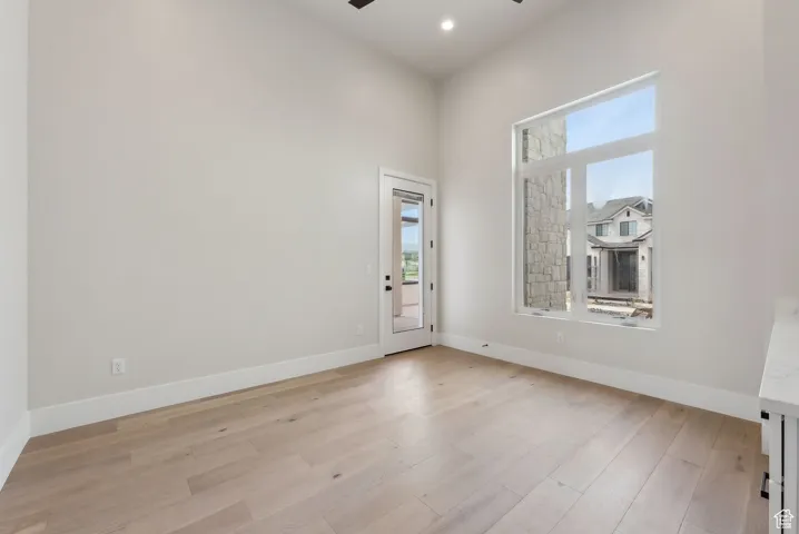 Unfurnished room featuring light wood-style floors, baseboards, ceiling fan, and a wealth of natural light