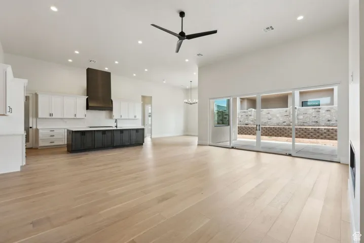 Unfurnished living room featuring light wood-style floors, a ceiling fan, recessed lighting, a towering ceiling, and visible vents