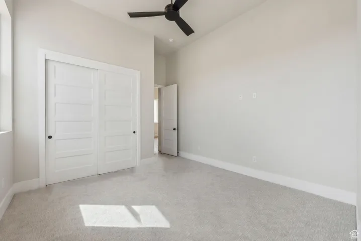 Unfurnished bedroom with light colored carpet, baseboards, vaulted ceiling, and a closet