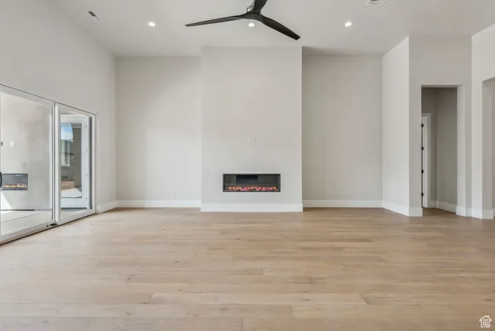 Unfurnished living room featuring recessed lighting, a ceiling fan, a glass covered fireplace, and light wood finished floors