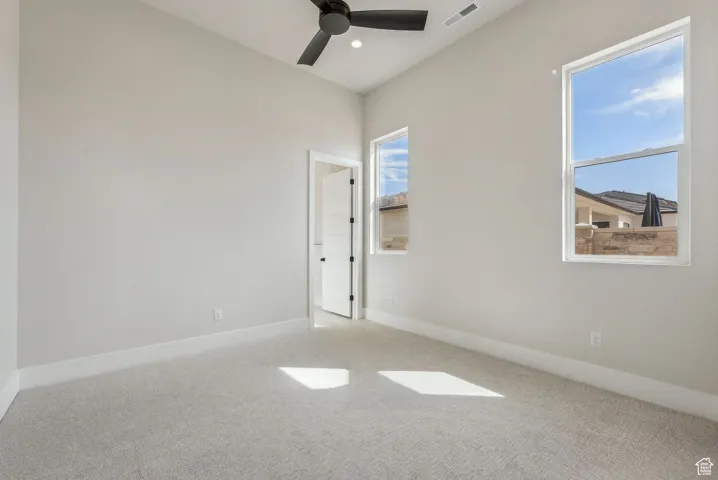 Unfurnished room featuring visible vents, a ceiling fan, baseboards, and carpet floors